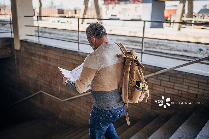 年长游客在火车站使用旅游地图图片素材
