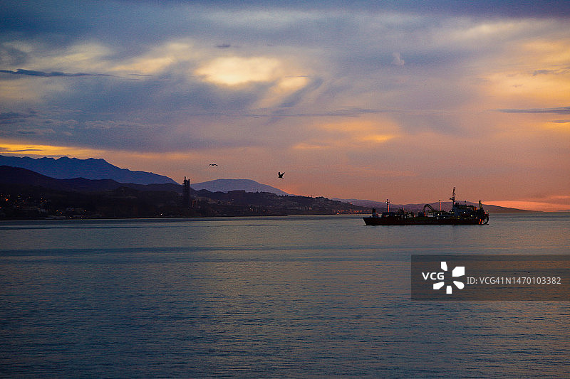 马拉加港停靠的船只上的彩色日出图片素材