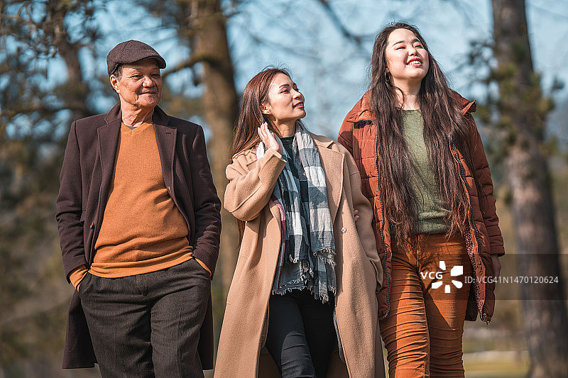 阳光明媚的冬日里在公园散步的亚洲家庭图片素材