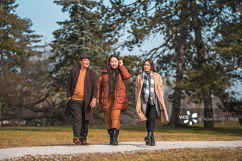 阳光明媚的冬日里在公园散步的亚洲家庭图片素材