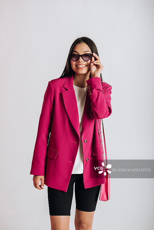 白色背景下，身穿玛莎拉红夹克的快乐年轻亚裔女模特肖像图片素材