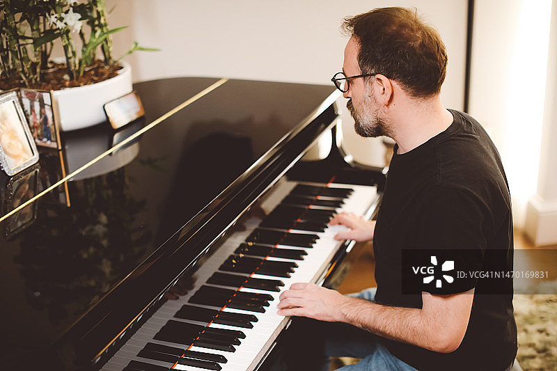 在家弹奏大钢琴的年轻男人图片素材