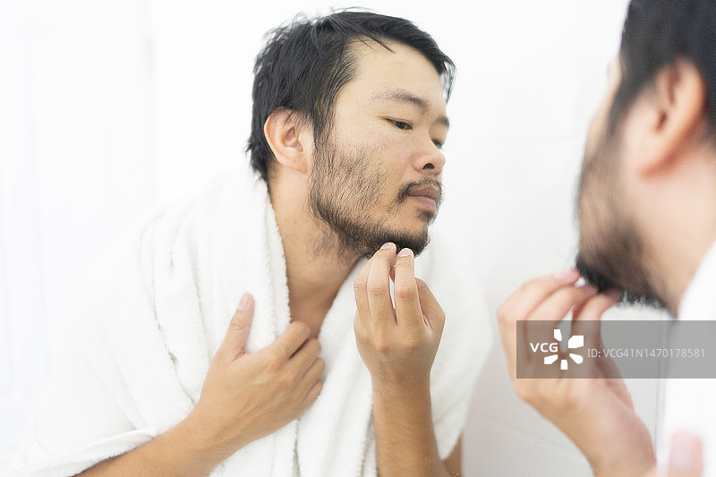 在浴室用镜子检查面部的亚洲成年男子图片素材