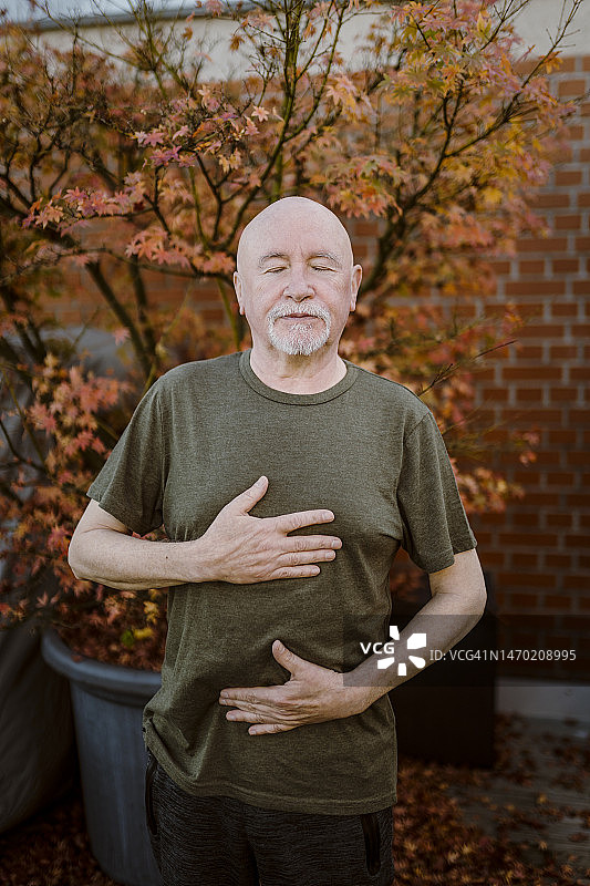 年长的男人靠着植物做呼吸运动图片素材