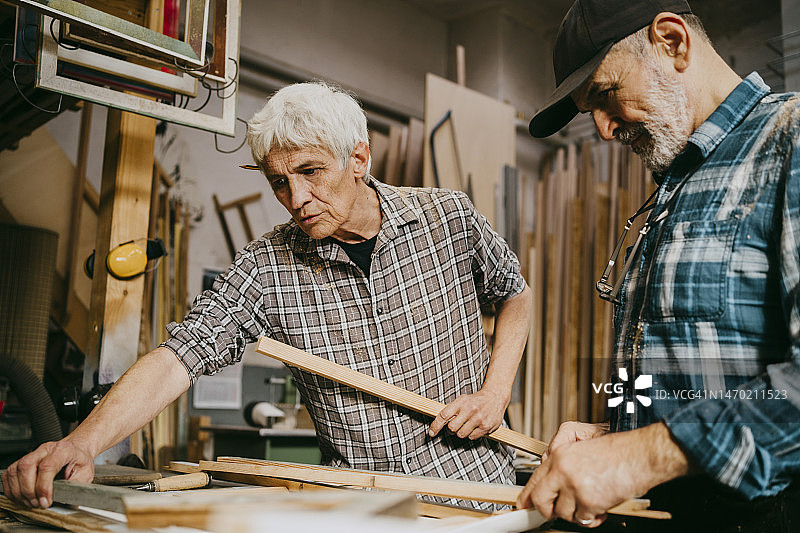 男木匠在修理店一起工作时向同事讲解图片素材