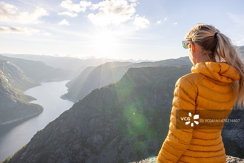 女人站在挪威峡湾顶端，沉思日落美景图片素材