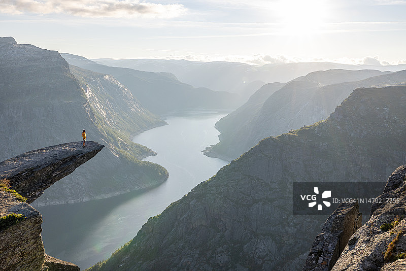 站在挪威著名巨岩Trolltunga（巨魔之舌）上的女人，俯瞰山谷全景图片素材