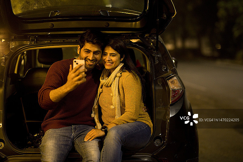 幸福情侣在路边晚上使用手机图片素材