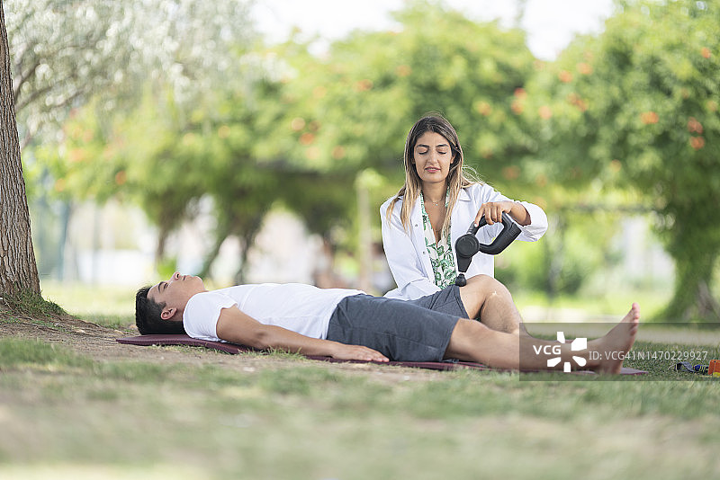女理疗师在树下为病人检查图片素材