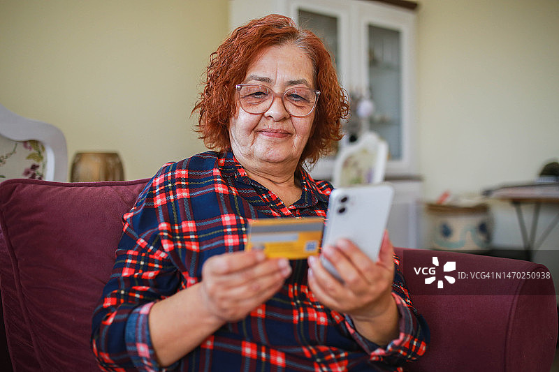 老年妇女在家里的客厅用手机取消信用卡，疑似欺诈图片素材