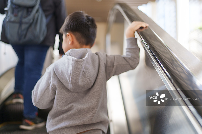 儿童在自动扶梯上抓住了扶手图片素材