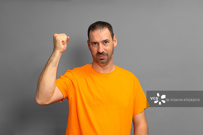 身穿橙色T恤庆祝的西班牙裔络腮胡男子图片素材