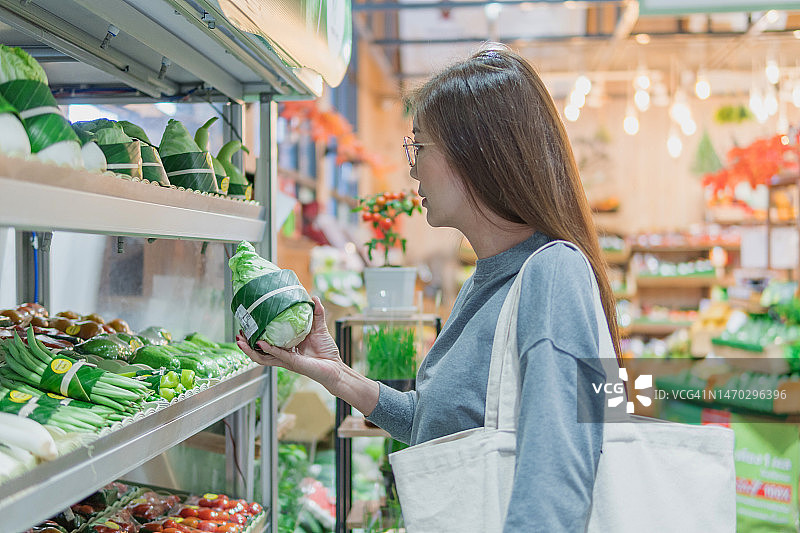 白人妇女拿着购物袋在超市购物，挑选新鲜有机蔬菜，健康饮食图片素材