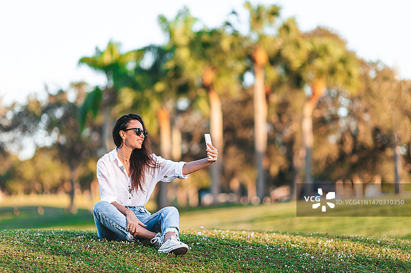 在公园户外使用手机的年轻女人图片素材