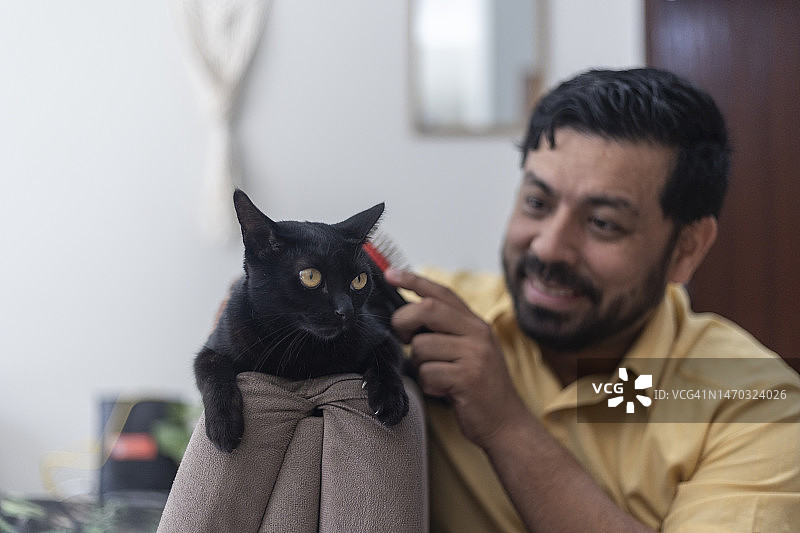 和宠物黑猫玩耍的拉丁裔男人图片素材