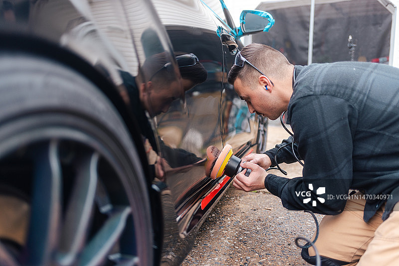 汽车美容：男子用抛光机抛光黑色汽车图片素材