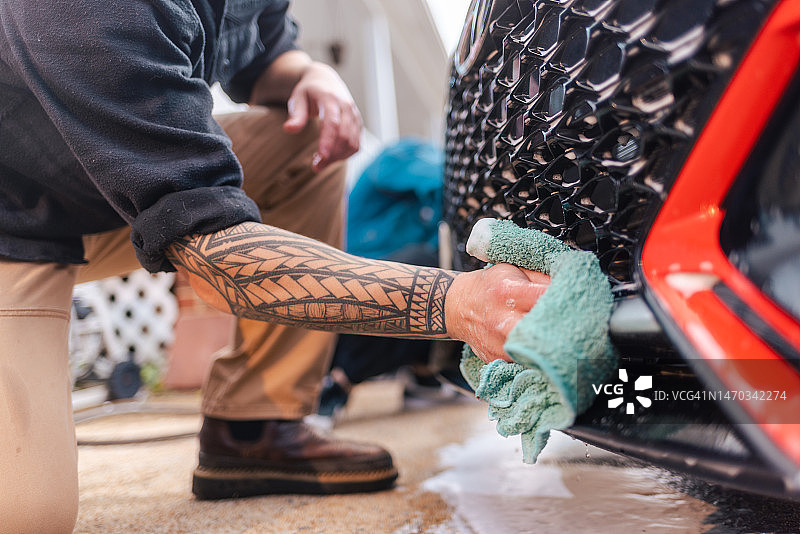 汽车美容：男人用超细纤维毛巾洗车特写图片素材