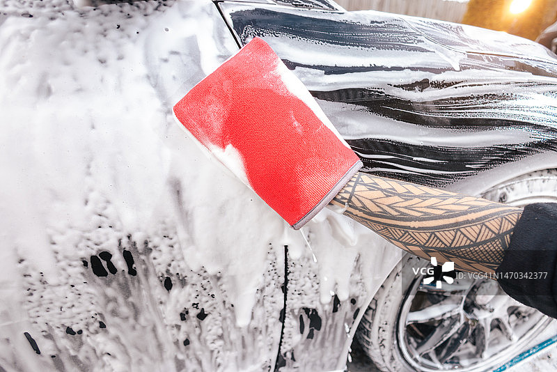 汽车细节：男人用超细纤维粘土手套清洗汽车图片素材