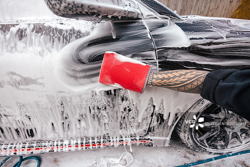 汽车细节：男人用超细纤维粘土手套清洗汽车图片素材