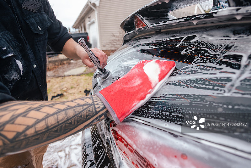 汽车细节：男人用超细纤维粘土手套清洗汽车图片素材