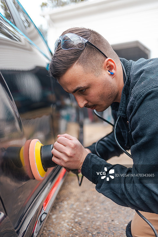 汽车美容：用双作用抛光机抛光黑色汽车，去除划痕，修复漆面-特写图片素材