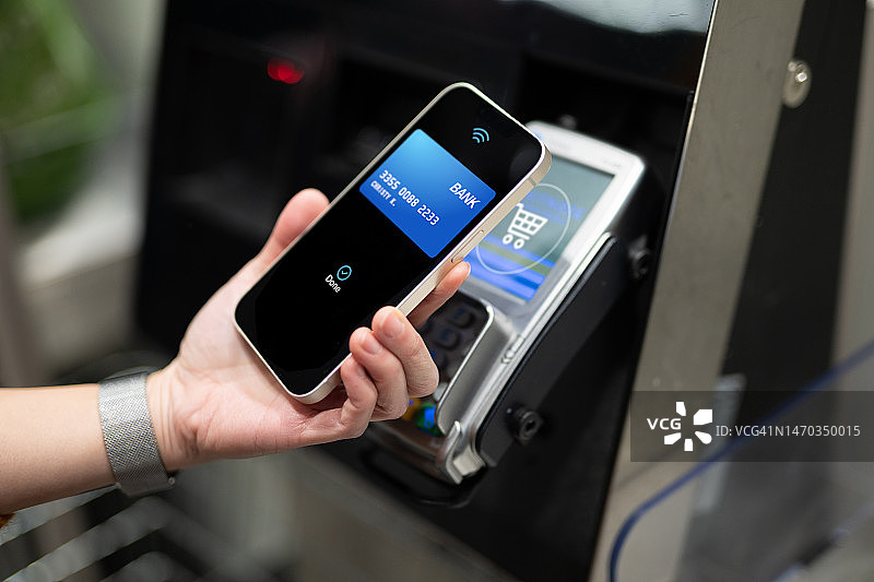 商店中女性用智能手机进行移动支付特写图片素材