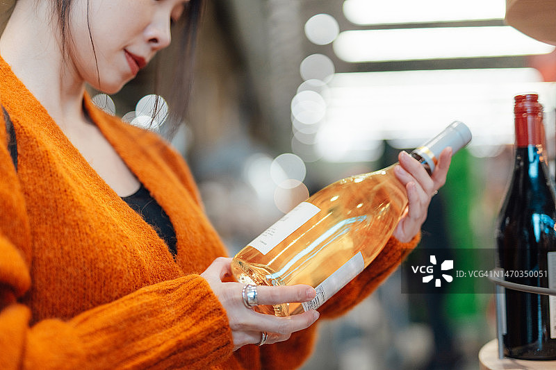 年轻的亚洲女人在超市挑选葡萄酒特写图片素材