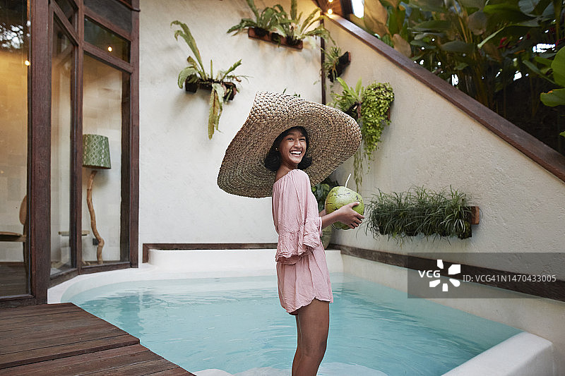 快乐的少女站在别墅的游泳池附近图片素材