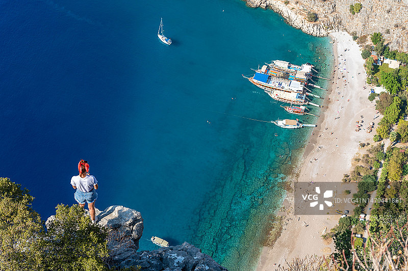 年轻女子在悬崖边愉快地观赏大海图片素材