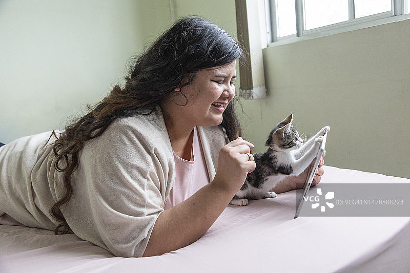 使用平板电脑和宠物小猫的拉丁裔女士图片素材
