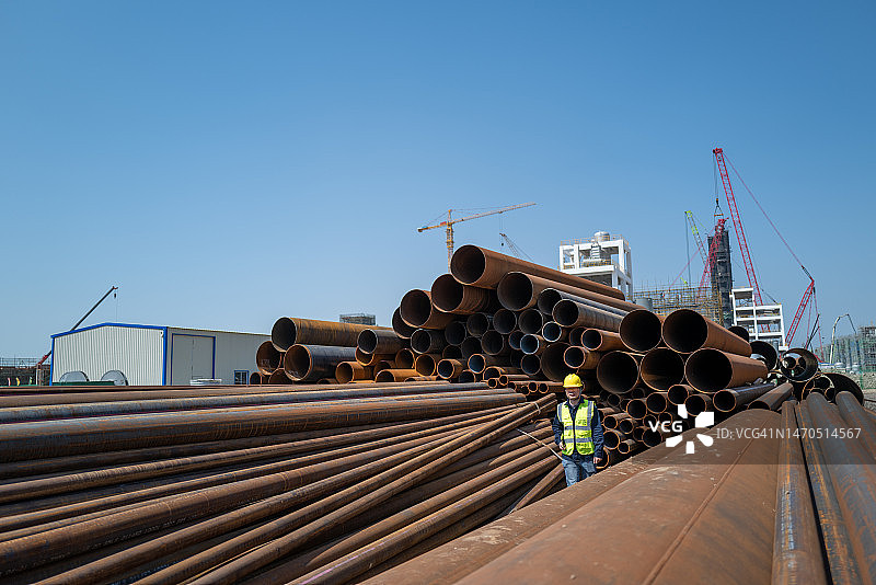 一名男工人在化工厂现场的钢管上行走图片素材