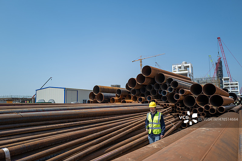 一名男工人在化工厂现场的钢管上行走图片素材