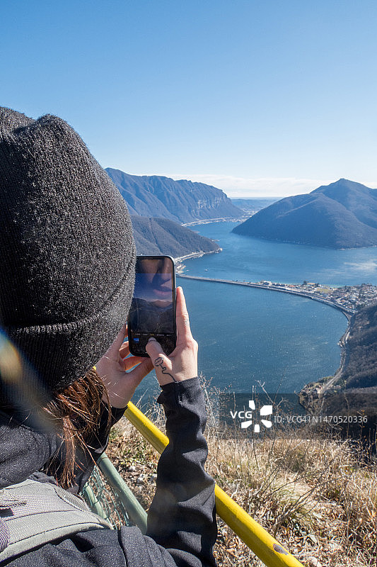 年轻女人在冬天登上山顶，用手机记录这一刻图片素材