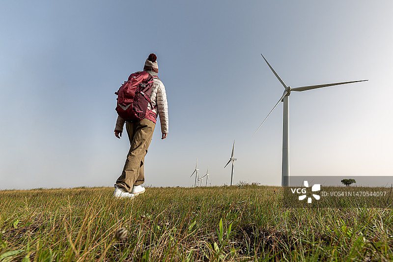 走向风力涡轮机的匿名徒步者图片素材