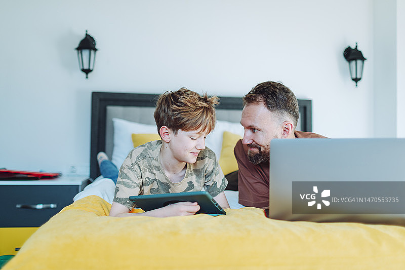父子使用笔记本电脑和平板电脑图片素材