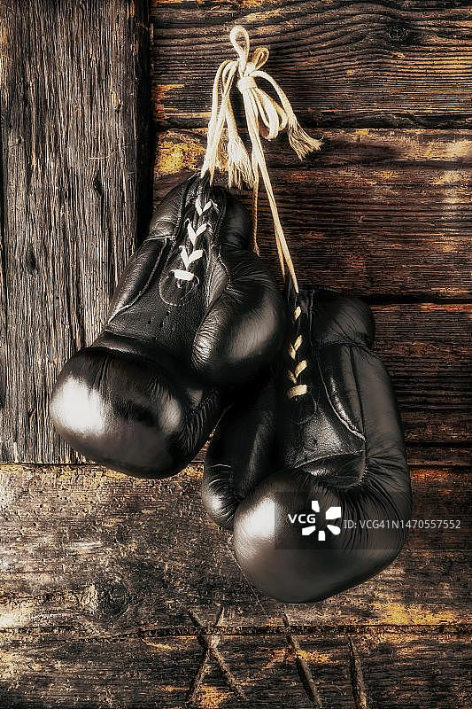 挂在质朴木墙前的旧皮革拳击手套，德国图片素材