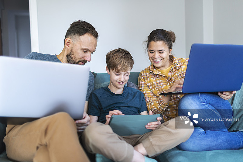 父亲、母亲和儿子使用笔记本电脑和平板电脑图片素材