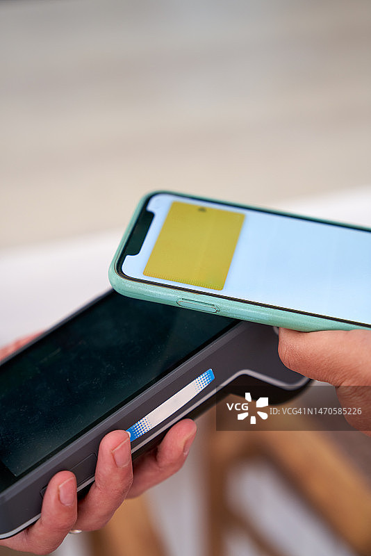 餐厅里用智能手机支付的匿名女人图片素材