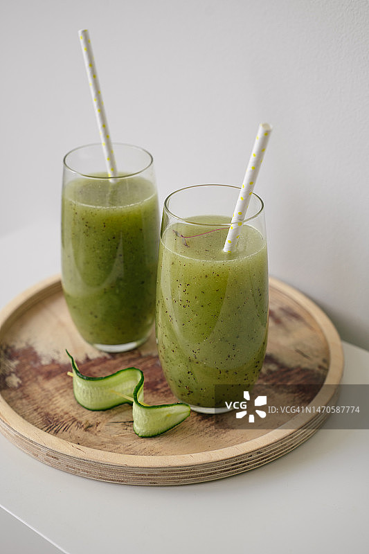 白色桌子上的两杯绿色冰沙，健康纯素饮食理念，新鲜有机饮品图片素材