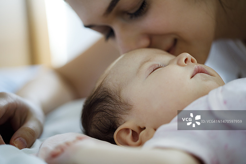 母亲亲吻熟睡的新生儿图片素材