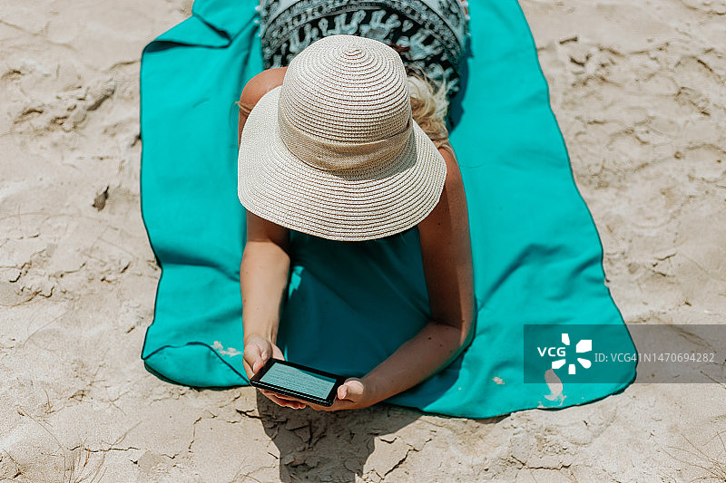 在海滩度假看电子书的女人图片素材