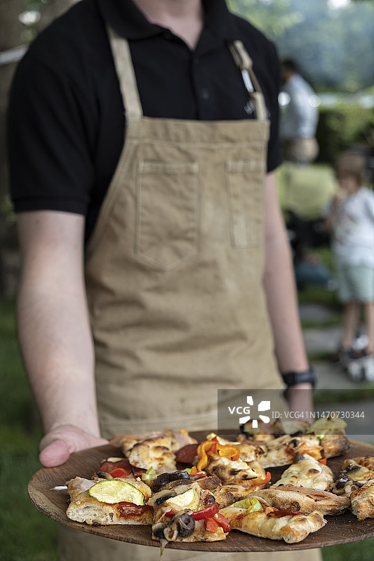 特写：在花园里提供披萨片的人图片素材