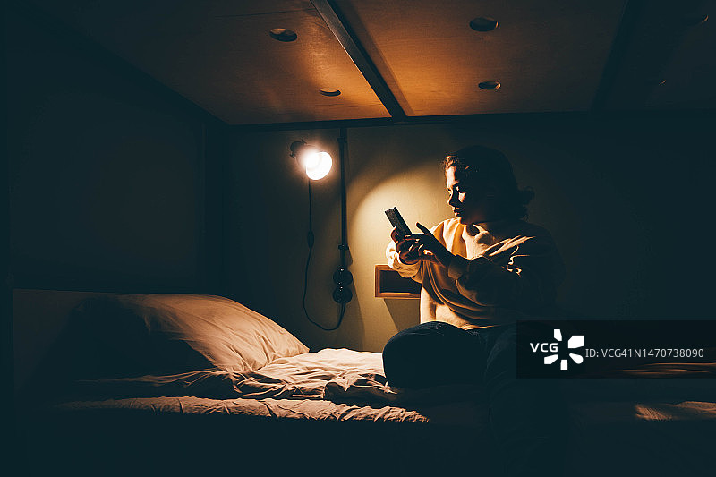 女人晚上在床上使用智能手机图片素材