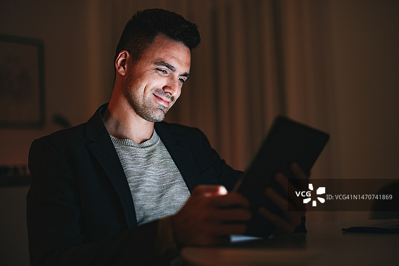 快乐的商人在家里的办公室晚上使用数位板图片素材
