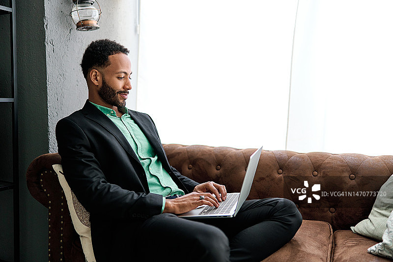坐在沙发上用笔记本电脑工作的商人图片素材