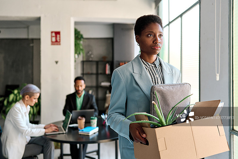 工人拿着装有个人物品的盒子离开办公室-裁员和失业概念图片素材
