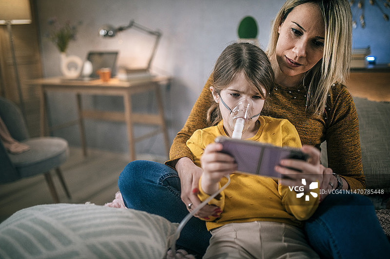 母亲帮助女儿在家使用哮喘吸入器图片素材