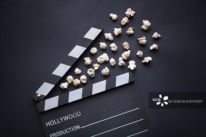 黑色背景上的电影场记板和爆米花图片素材