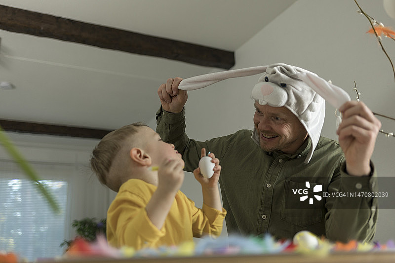 父亲和孩子戴着兔子耳朵装饰复活节彩蛋图片素材