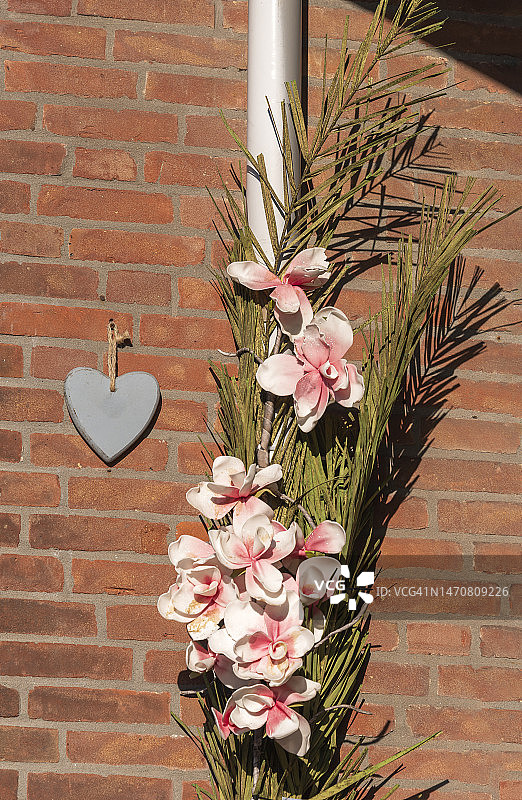 悬挂在石墙上的人造花艺图片素材